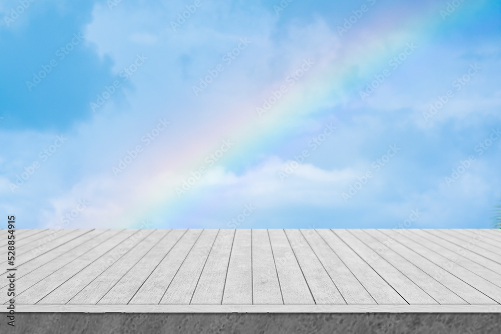 White wooden table with sky and rainbow background.