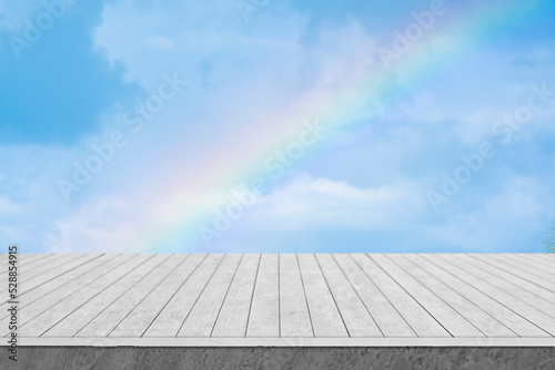 White wooden table with sky and rainbow background.