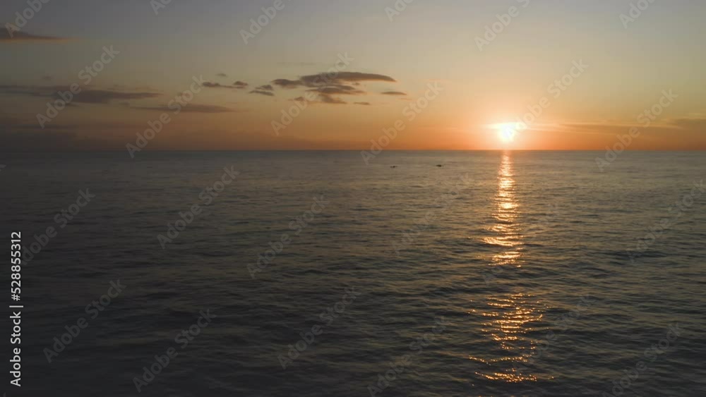 Aerial view of sunset above ocean with dark silhouettes of two Jukung fishing boats. Sea water reflecting orange sunset sun with clouds. Peaceful dawn scene with fishermen and motorboat Aerial view of sunset above ocean with dark silhouettes of two Jukung fishing boats. Sea water reflecting orange sunset sun with clouds. Peaceful dawn scene with fishermen and motorboat