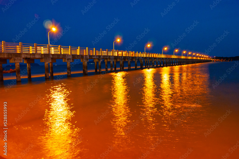 Obraz premium Pier at night with yellow lights on a background of blue sky