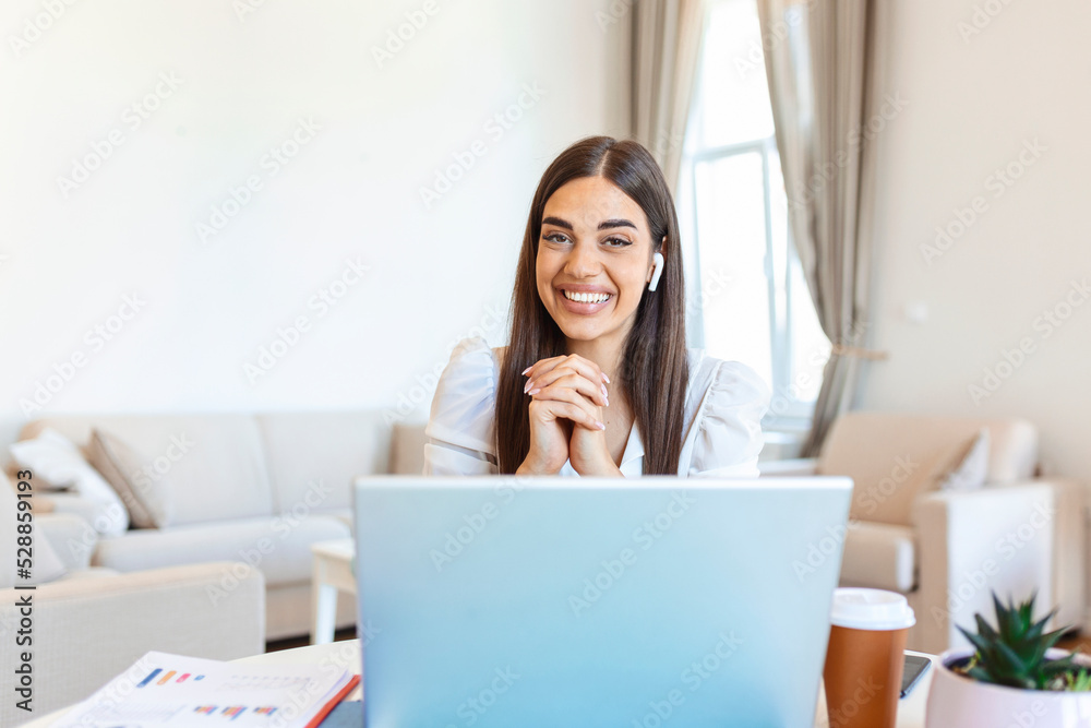Excited young woman looking at camera, holding funny conversation with colleagues online, webcam view. Head shot of young woman with headphones laughing, having fun from home office. Excited young woman looking at camera, holding funny conversation with colleagues online, webcam view. Head shot of young woman with headphones laughing, having fun from home office.