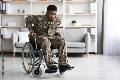 Unhappy african american veteran in wheelchair trying to get up