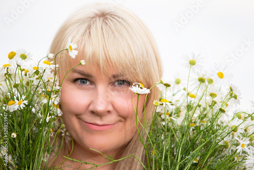 A beautiful plus size woman with white hair holds a bouquet of daisies, smiles, enjoys summer and life.