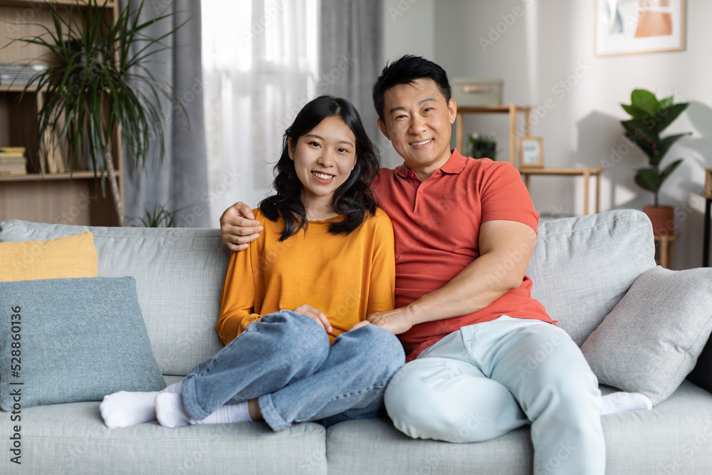 Loving chinese couple bonding on couch at home