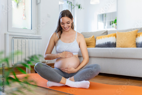 pregnant woman training yoga, caressing her belly. Young happy expectant relaxing, thinking about her baby and enjoying her future life. Motherhood, pregnancy, yoga concept