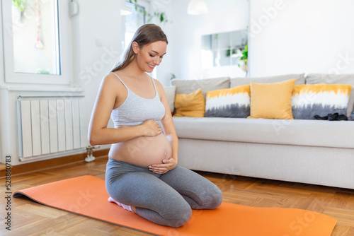 pregnant woman training yoga, caressing her belly. Young happy expectant relaxing, thinking about her baby and enjoying her future life. Motherhood, pregnancy, yoga concept