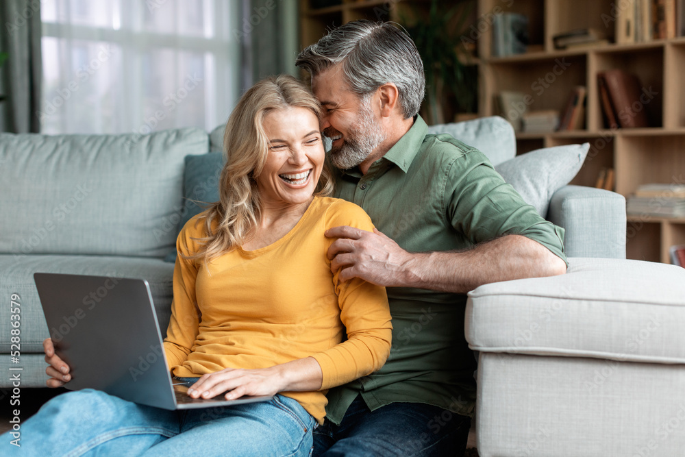 Happy Moments. Romantic Middle Aged Spouses Using Laptop And Bonding At Home Happy Moments. Romantic Middle Aged Spouses Using Laptop And Bonding At Home
