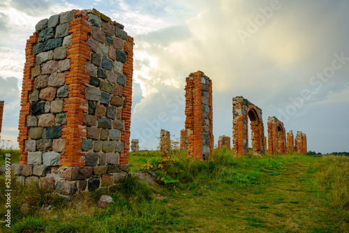 The remains of a stone column from an old building in the middle of a field on a sunny spring day. City Smiltene, Latvia. Old brick stonehenge photo