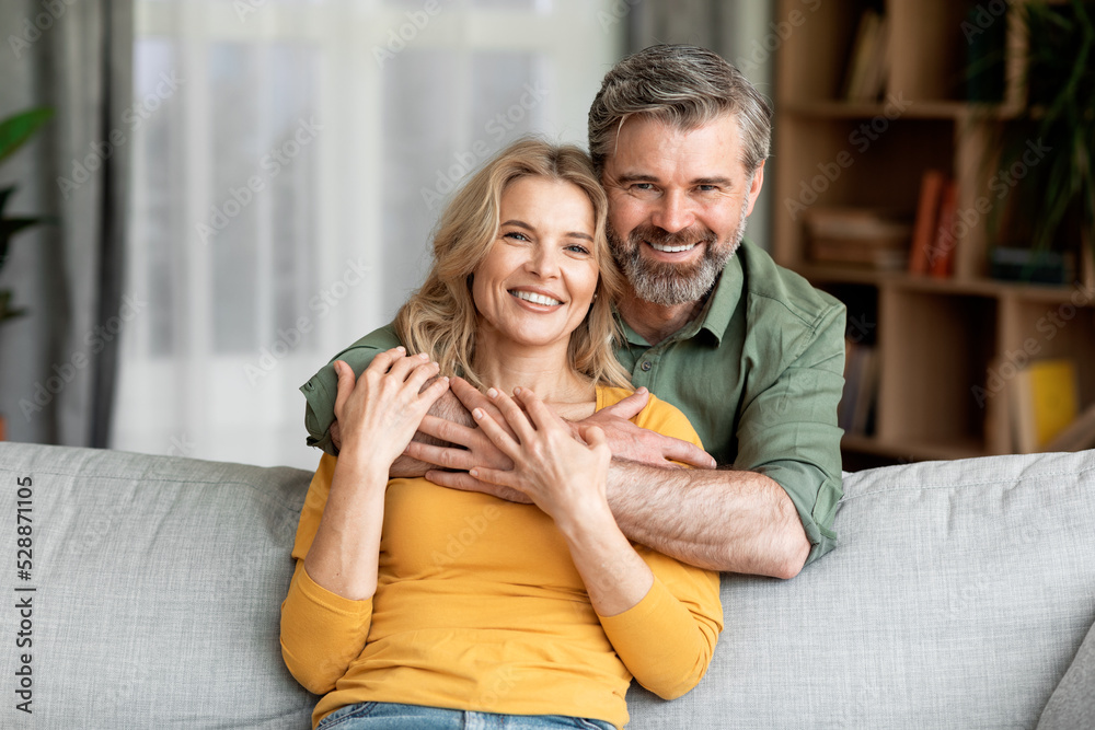 Portrait Of Smiling Middle Aged Spouses Posing In Home Interior Portrait Of Smiling Middle Aged Spouses Posing In Home Interior