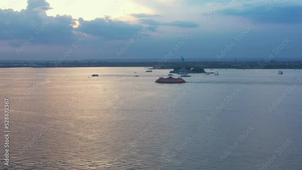 Aerial rising tilt zoom of New York Harbor with the Staten Island Ferry and the Statue of Liberty at dramatic sunset dusk Aerial rising tilt zoom of New York Harbor with the Staten Island Ferry and the Statue of Liberty at dramatic sunset dusk