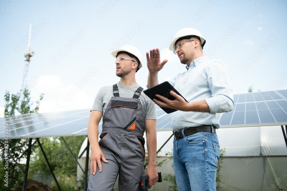 near the solar panels, the employee shows the work plan to the boss.