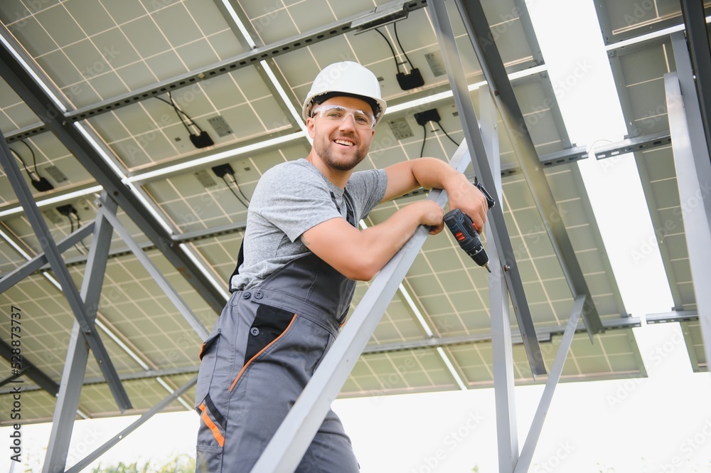 Male engineer in protective helmet installing solar photovoltaic panel system. Alternative energy ecological concept.