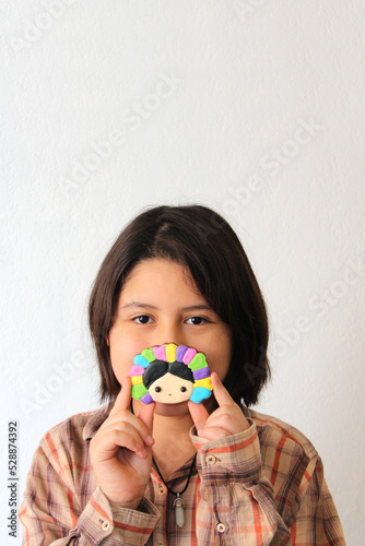 10 year old Hispanic Latina girl shows her favorite toy and dessert in the form of a traditional Mexican doll with colored ribbons in her hair proud of her culture and tradition in Mexicco
 photo