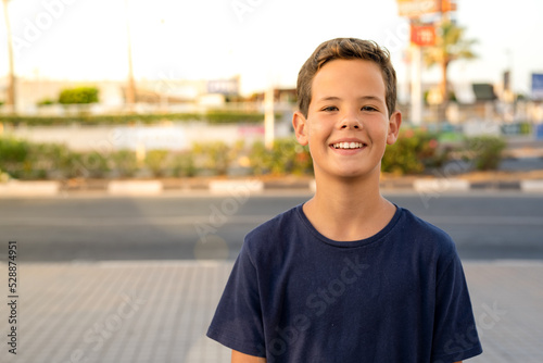 Portrait of cheerful happy young boy standing in the city.