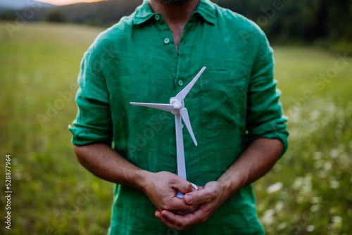 Close up of man standing in nature with model of wind turbine. Concept of ecology future and renewable resources. © Halfpoint