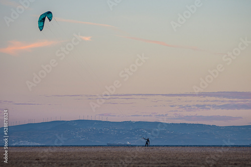 Kitesurfer on the beach at sunset