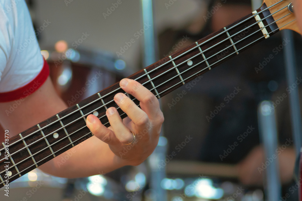 Fingers on strings of an electric bass guitar