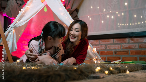 Happy family. Time for stories. Delighted happy cute mother and son enjoying a book before sleeping and using a flashlight.