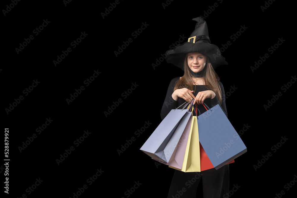 Teenage girl in pointy hat with multi-colored paper shopping bags in isolation on black background. Copy space. Black Friday Concept.