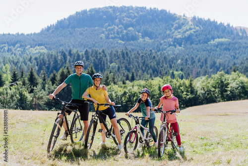 Young family with children at bike trip,posing with bicycles in nature.