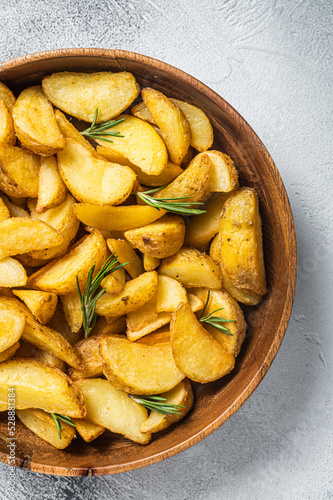 Roasted potato wedges with rosemary, organic vegetarian potato wedges meal. White background. Top view