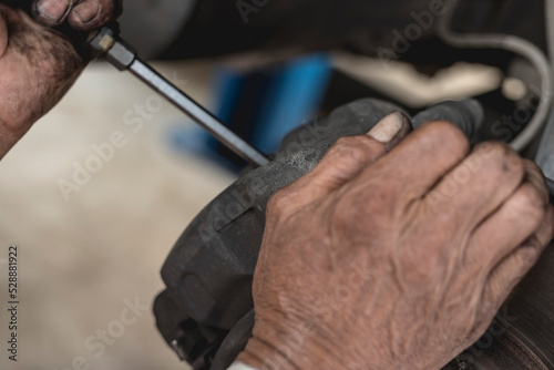 A mechanic pries off the brake caliper off of the brake pads with a screwdriver. Old brake pad removal procedure. photo