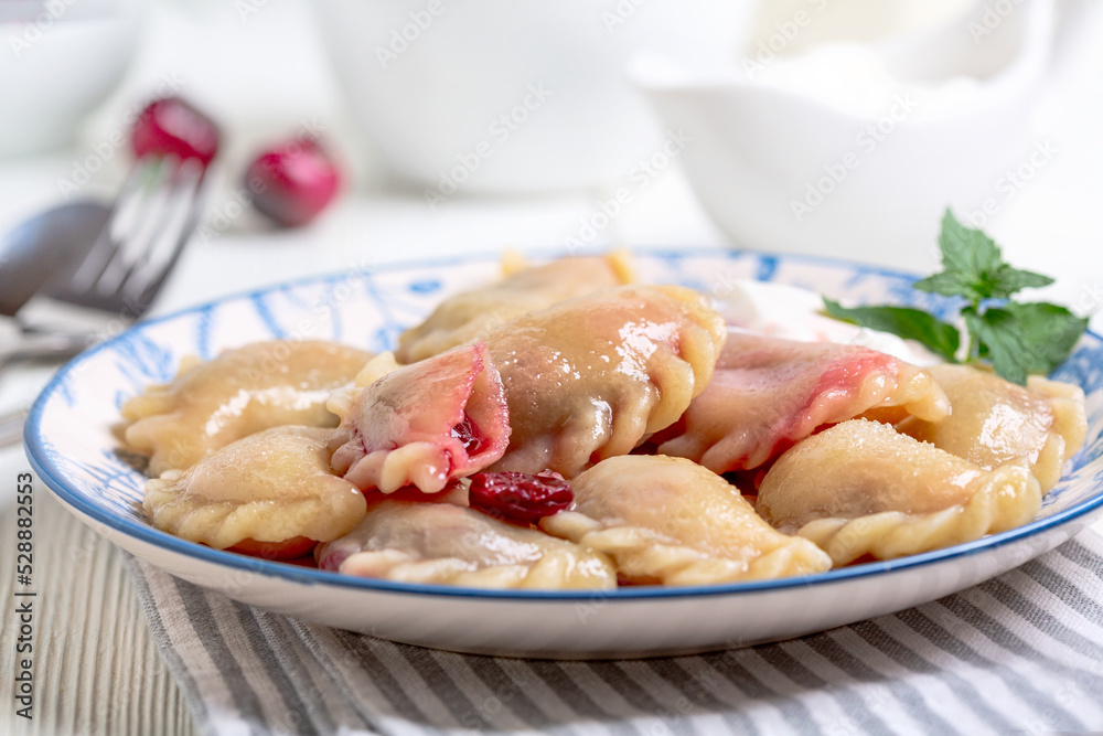 Cherry pierogies with sour cream sauce.