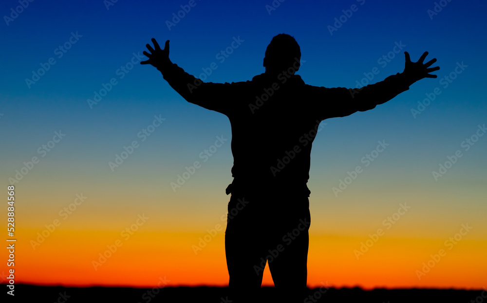 Silhouette of a person on the background of a yellow-blue sky.