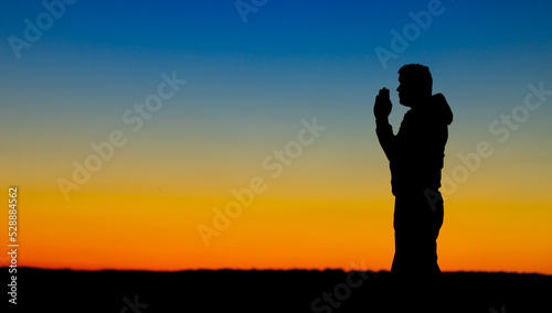 Fototapeta Naklejka Na Ścianę i Meble -  Silhouette of a person on the background of a yellow-blue sky.