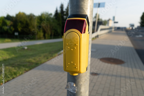 Pedestrian crossing button with light warning at a street crosswalk.