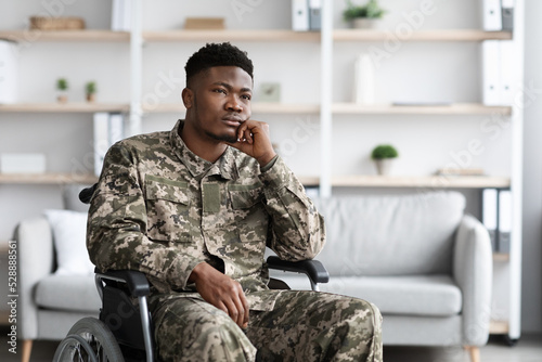 Depressed black man sitting in wheelchair, looking at copy space © Prostock-studio
