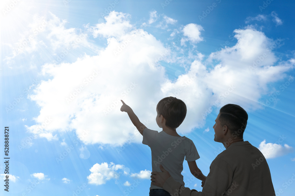 Godparent with child pointing at blue sky with white clouds Godparent with child pointing at blue sky with white clouds