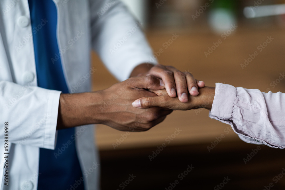Fototapeta premium Unrecognizable man doctor supporting patient, holding hand