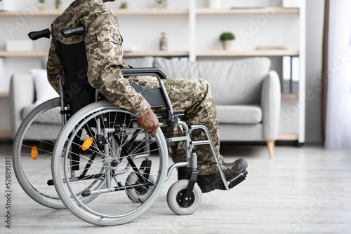 Foto Cropped of black veteran in wheelchair rolling by home