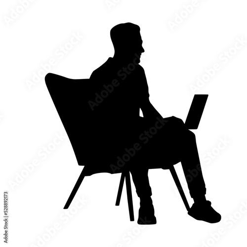 silhouette of a man sitting on a chair while using a laptop