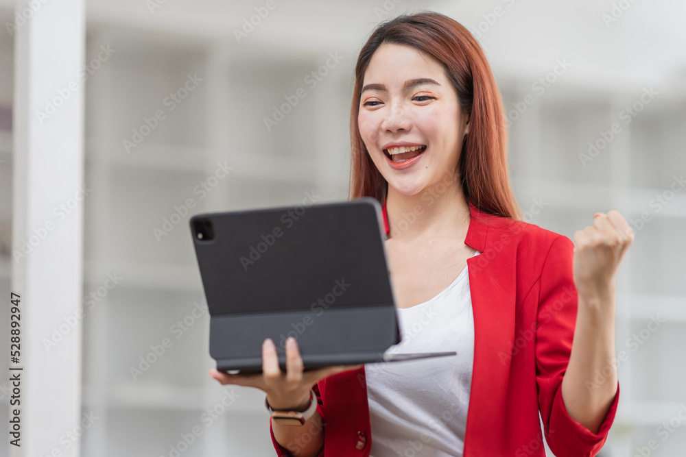 Fototapeta premium Excited happy woman looking at the tablet screen, celebrating an online win, overjoyed young asian female screaming with joy, isolated over a white blur background 