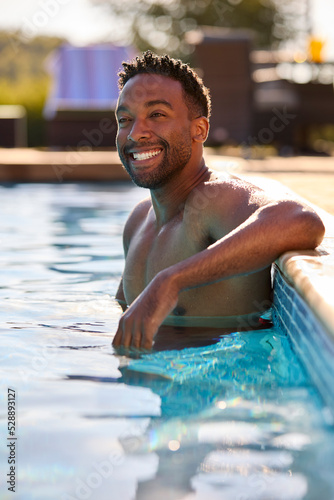 Portrait Of Smiling Man On Summer Holiday Relaxing In Swimming Pool