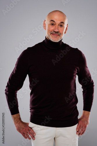 Studio portrait of handsome middle aged man wearing turtleneck sweater while standing at isolated background