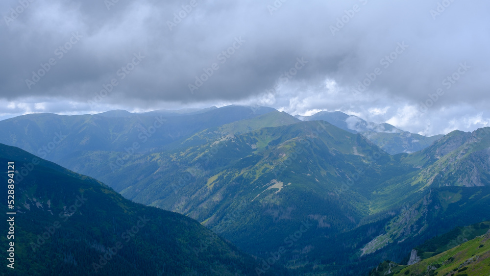 low hanging storm clouds and fog in the mountains on a summer day. blue haze in mountain valleys. it will rain