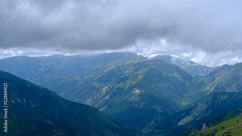 Fototapeta Naklejka Na Ścianę i Meble -  low hanging storm clouds and fog in the mountains on a summer day. blue haze in mountain valleys. it will rain