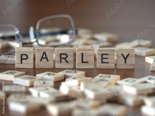 parley word or concept represented by wooden letter tiles on a wooden table with glasses and a book