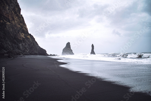 Iceland Reynisdrangar rocks at black sand beach seascape with cloudy sky