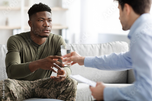 Therapist passing glass of water to his patient military man