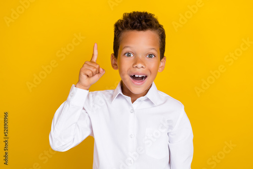 Photo of overjoyed boy wear trendy clothes raise arm hand evrika brilliant excellent answer solution isolated on yellow color background