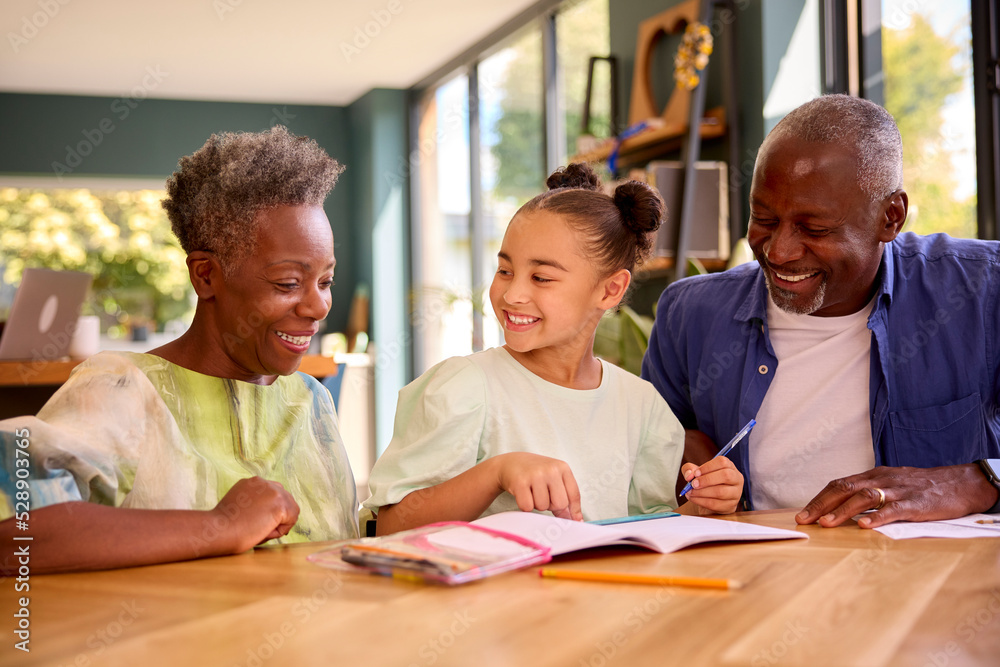 Multi-Generation Family With Grandparents Helping Granddaughter With School Work At Home Multi-Generation Family With Grandparents Helping Granddaughter With School Work At Home