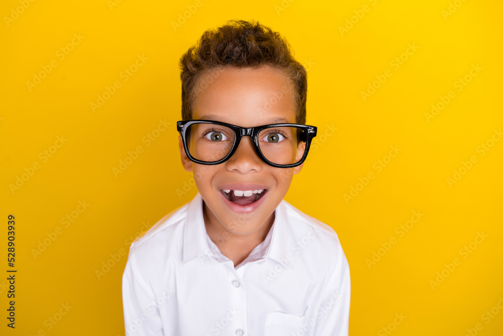 Close up photo of cheerful boy learner first time wear glasses enjoy rejoice look camera isolated on yellow color background