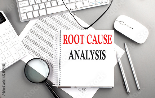 ROOT CAUSE ANALYSIS text on notepad on chart with keyboard and calculator on grey background