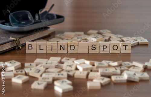 blind spot word or concept represented by wooden letter tiles on a wooden table with glasses and a book