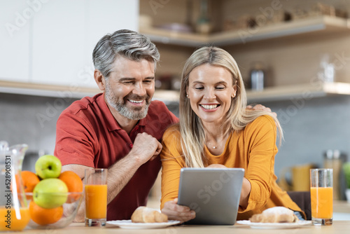 Loving couple enjoying healthy breakfast  using digital tablet