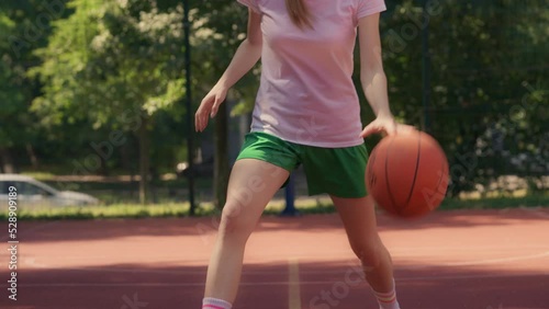 Beautiful female basketball player dribbling ball on court, active lifestyle